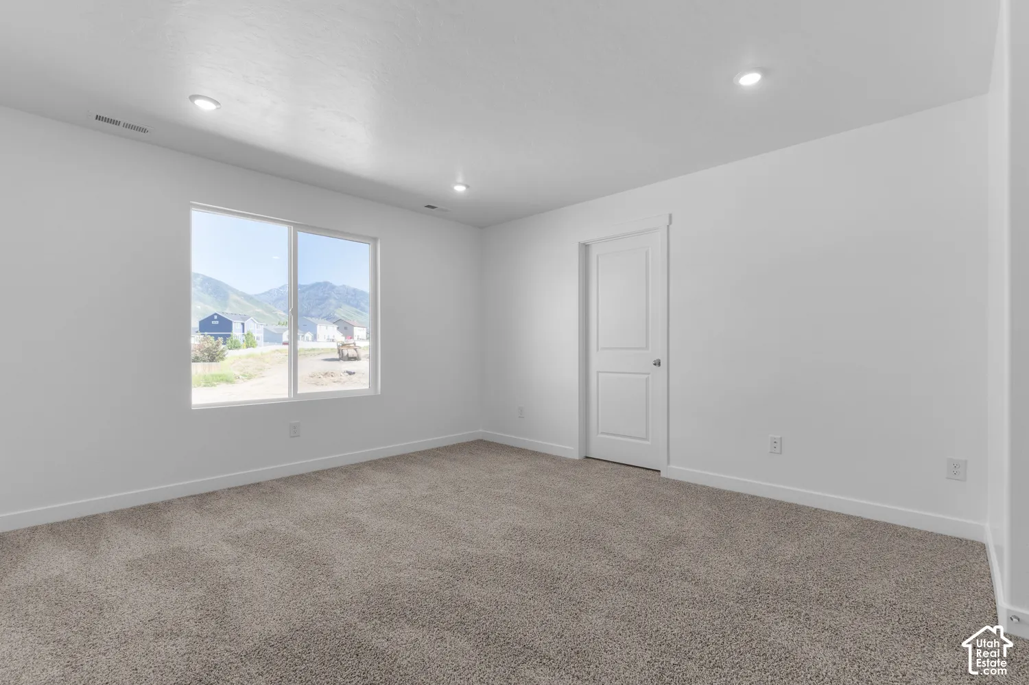 Recessed lighting, neutral wall tones, window with mountain backdrop, two-panel interior door, and carpeted flooring
