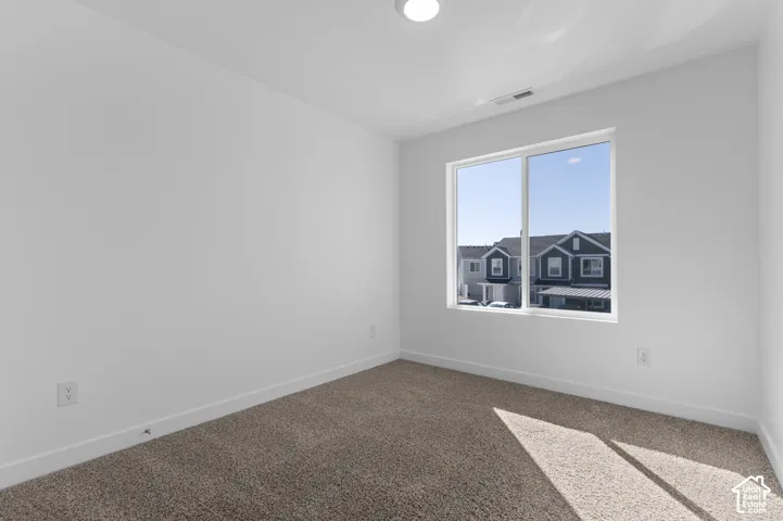 Recessed ceiling lighting, carpeted flooring, white walls, and a large window