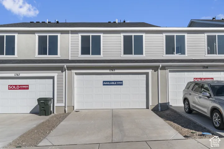 Two-story townhouse exterior with light gray siding and stucco accents