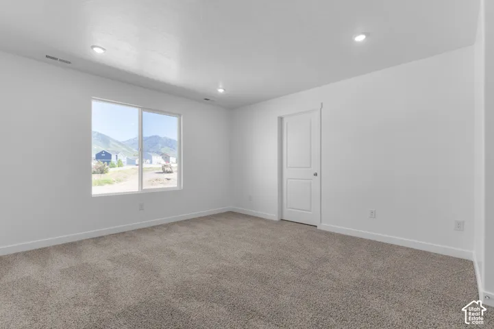 Recessed lighting, neutral wall tones, window with mountain backdrop, two-panel interior door, and carpeted flooring