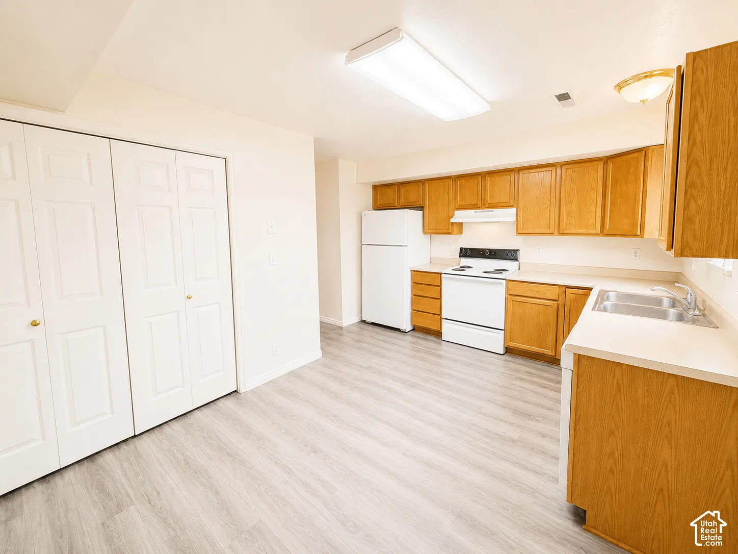 Spacious kitchen featuring wood-finish cabinetry, white appliances, laminate countertops, and a large island with additional counter space