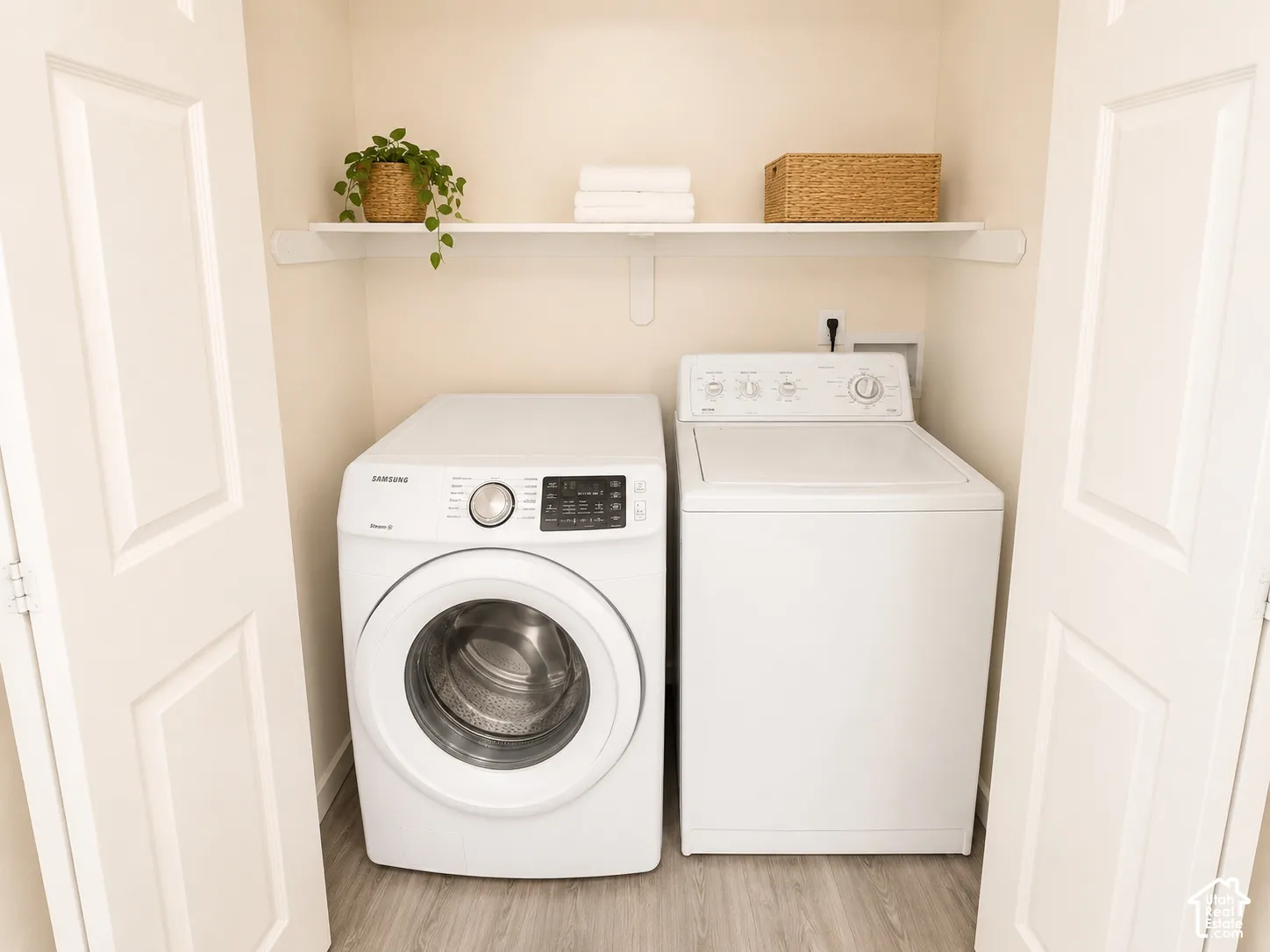 Built-in laundry closet with wood-finish flooring, a white wall shelf, and panel doors