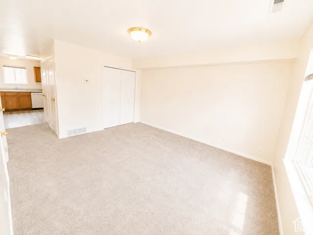 Neutral-toned carpet flooring, a ceiling-mounted light fixture, and a window with natural light