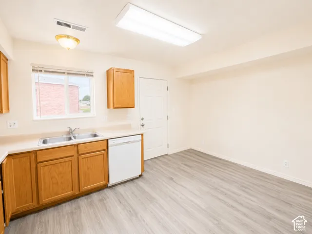 Bright utility kitchen featuring wood-finish cabinetry, white appliances, stainless steel sink, and ample counter space
