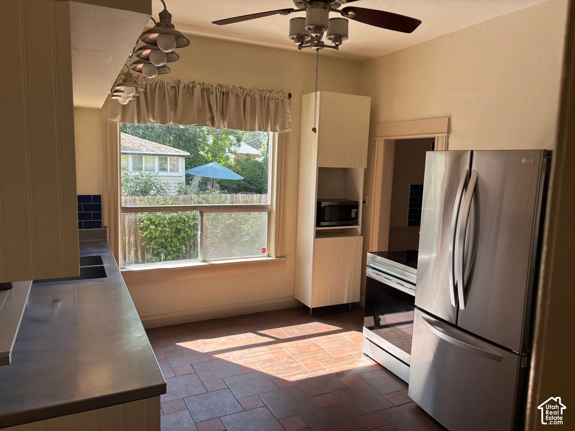 Stainless steel refrigerator and range, ceiling fan with light fixture, recessed lighting, and tile flooring
