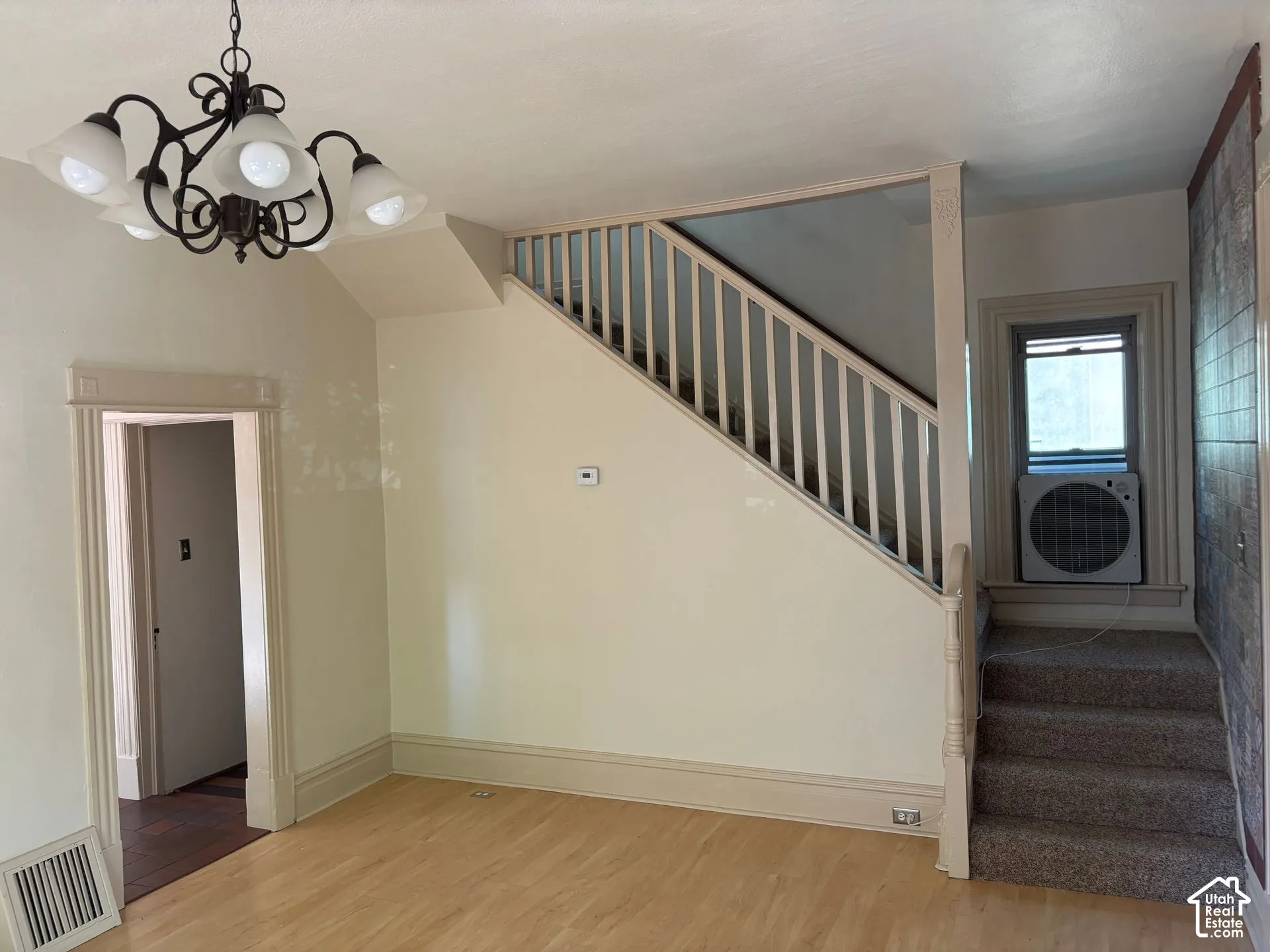 Wood-finish flooring, staircase with painted balusters, built-in chandelier, and decorative baseboards