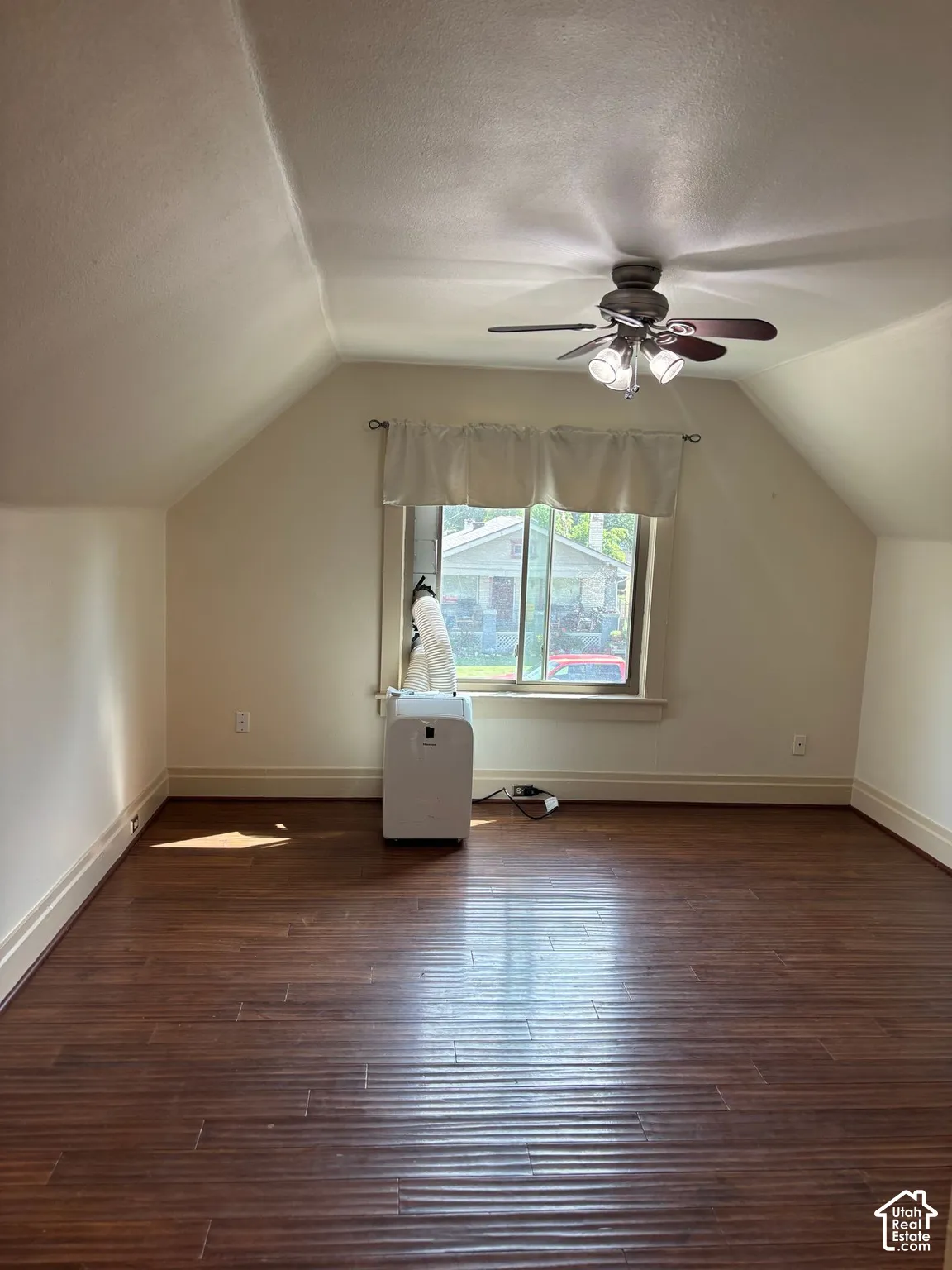 Angled ceiling lines, wood-finish flooring, and a ceiling fan with integrated lighting