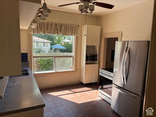Stainless steel refrigerator and range, ceiling fan with light fixture, recessed lighting, and tile flooring