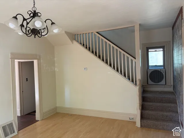 Wood-finish flooring, staircase with painted balusters, built-in chandelier, and decorative baseboards