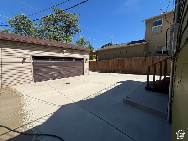 Detached garage with horizontal siding, a brown panel garage door, and a concrete driveway