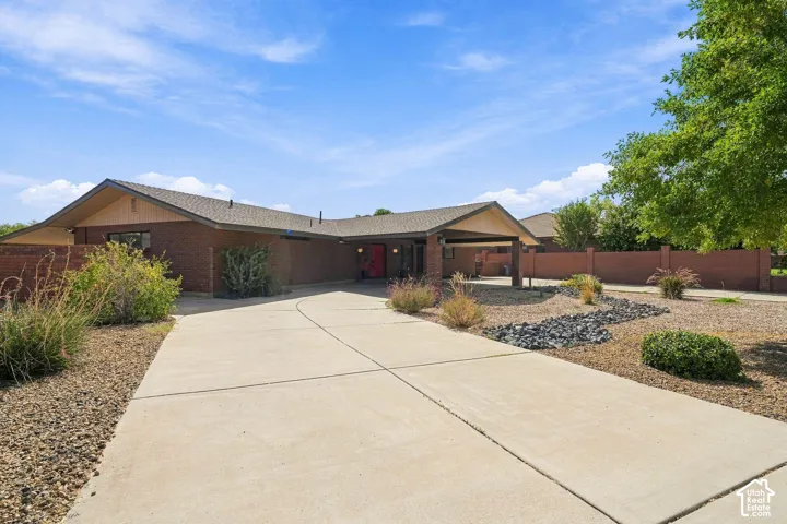 Brick exterior with a covered entryway, attached carport, concrete driveway, and low-maintenance landscaping