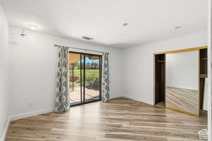 Wood-finish flooring with white baseboards, sliding glass doors to outdoor patio, and recessed lighting