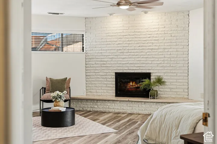 Built-in fireplace with a stone surround, wood-finish flooring, recessed lighting, and a ceiling fan