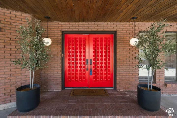 Brick exterior with a wood-paneled ceiling, featuring red double entry doors with decorative panels