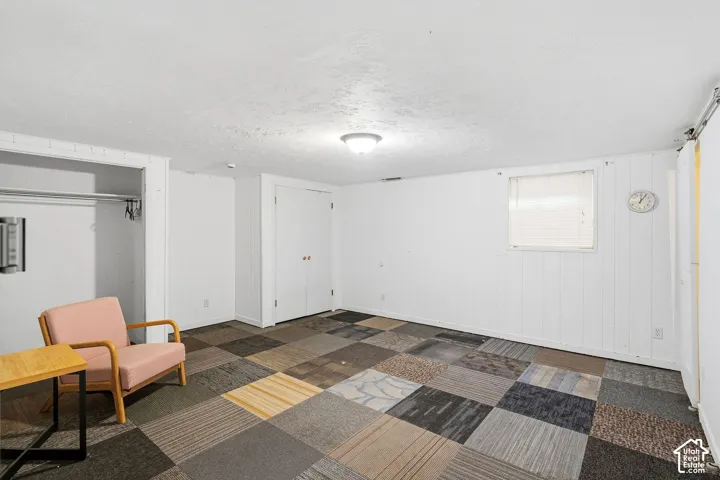 Room featuring multi-toned carpet squares, white paneling, and a flush-mount ceiling light