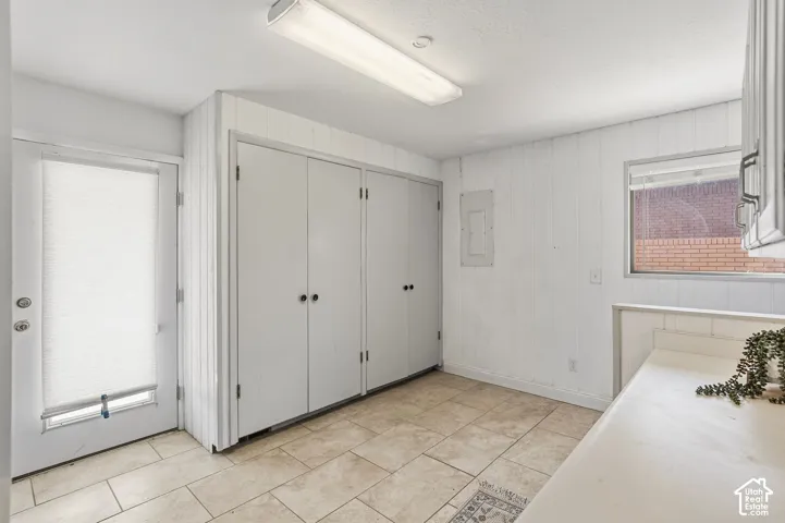 Tile flooring, white wall paneling, built-in storage closets, recessed lighting, and a white countertop