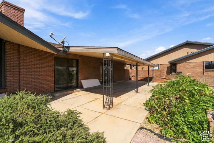 Brick exterior with covered patio featuring concrete flooring and decorative metal supports