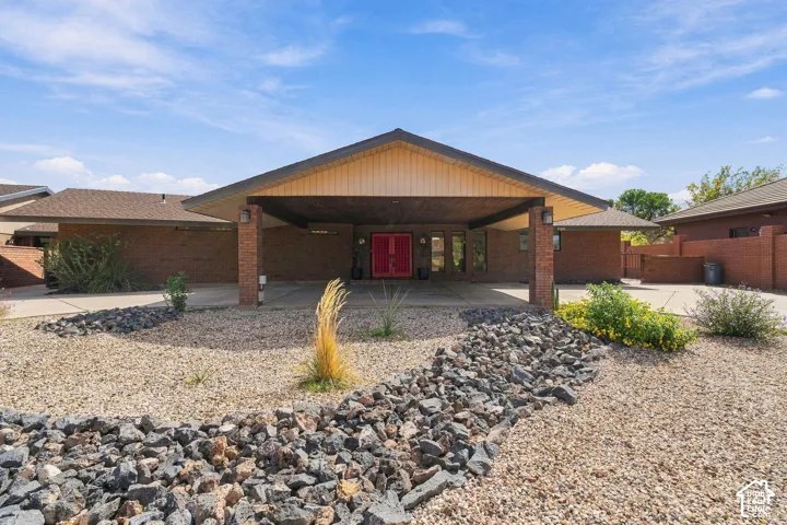 Brick exterior with a covered entryway and red double entry doors