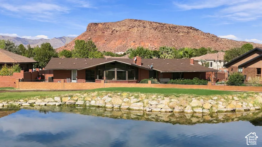 Waterfront property featuring a brick exterior, expansive windows, and a prominent red rock mountain backdrop