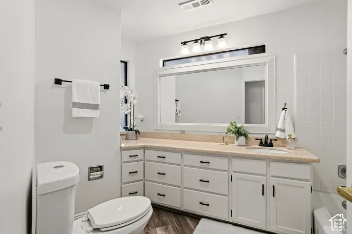 White vanity with black hardware, light-colored countertop, single basin sink, and an expansive mirror