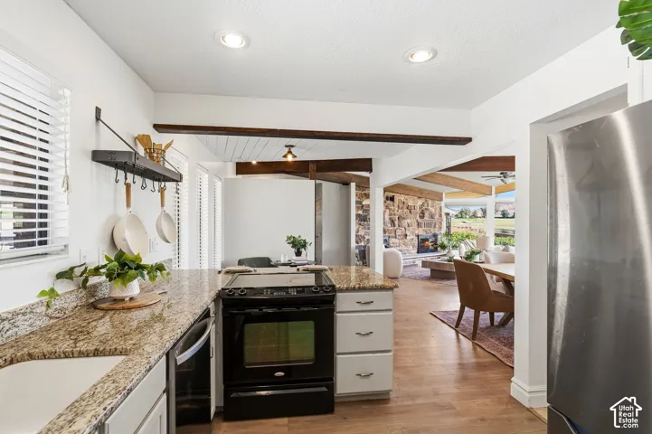 Granite countertops, integrated farmhouse sink, black electric range, wood-finish flooring, and recessed lighting