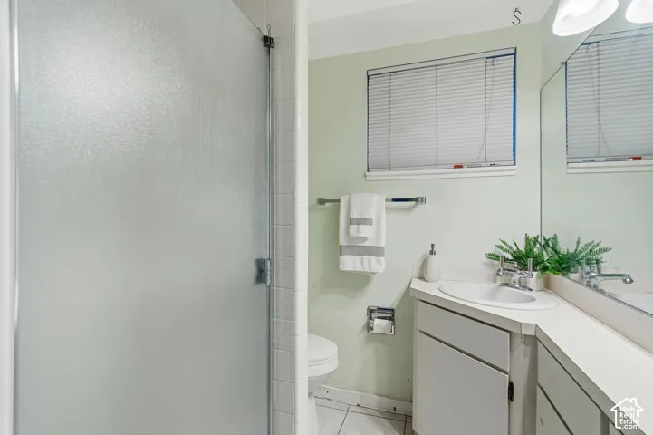 Frosted glass shower enclosure, single vanity with integrated sink, chrome faucet, wall-mounted mirror, and horizontal blinds