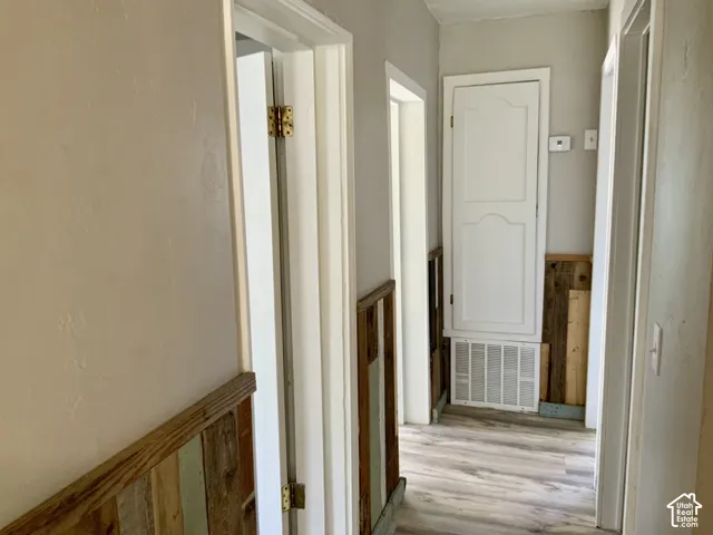 Wood-finish flooring, paneled wall accents, white trim, and a built-in cabinet