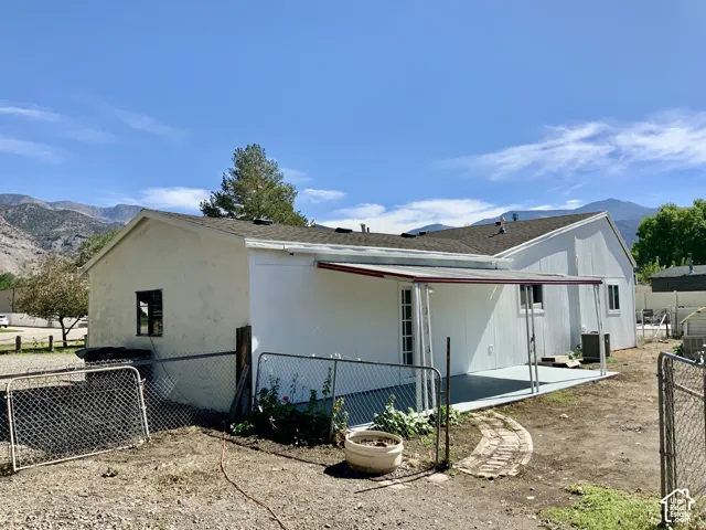 Rear exterior with covered patio, brick pathway, and chain-link fencing