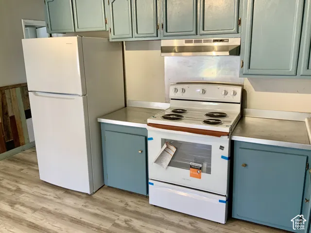Kitchen featuring painted cabinetry, stainless steel range hood, white electric range, white refrigerator, and wood-finish flooring