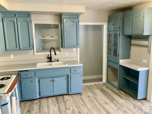 Updated kitchen featuring soft blue cabinetry with hardware accents, white quartz countertops, and a black faucet