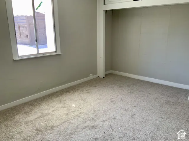 Carpeted flooring, neutral wall color, and a window with white trim