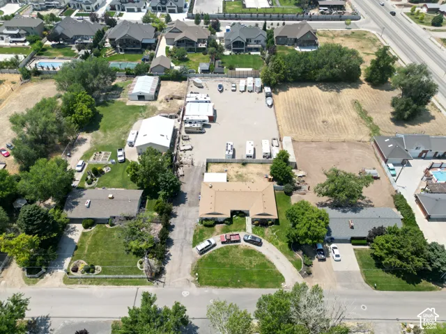 Expansive lot featuring multiple structures, paved and unpaved areas, mature trees, and a road frontage