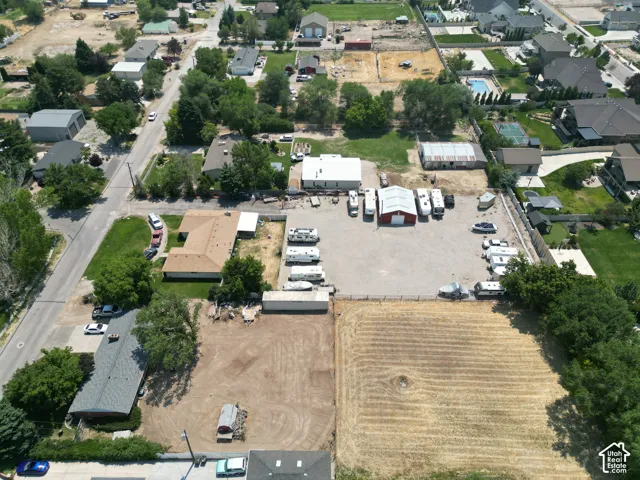 Aerial perspective highlighting multiple structures, expansive gravel lot, and surrounding residential properties