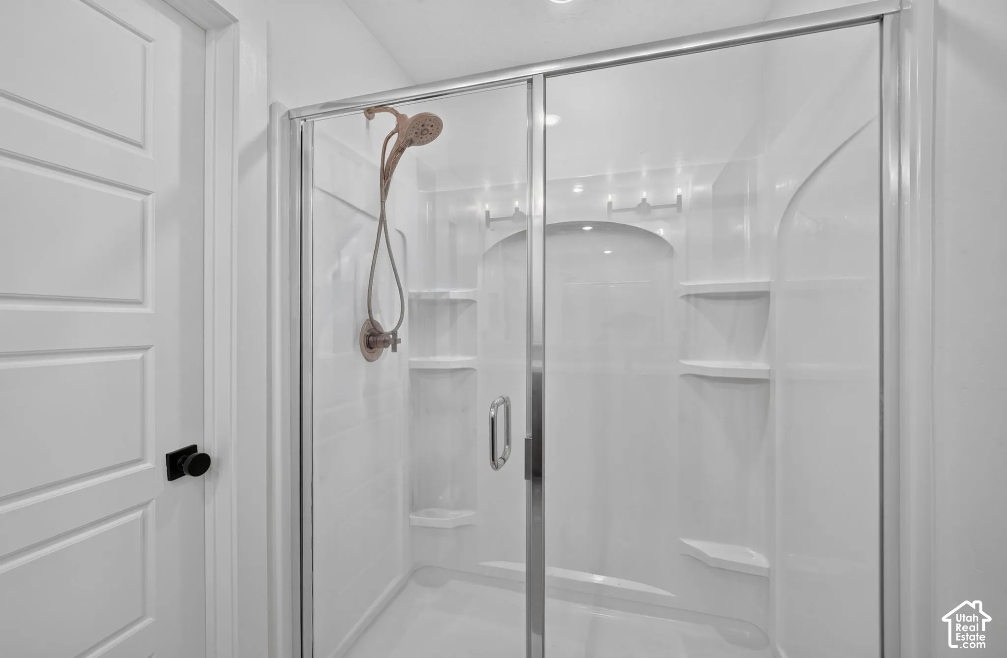 Shower enclosure with glass sliding doors, integrated shelving, and a bronze-finish showerhead