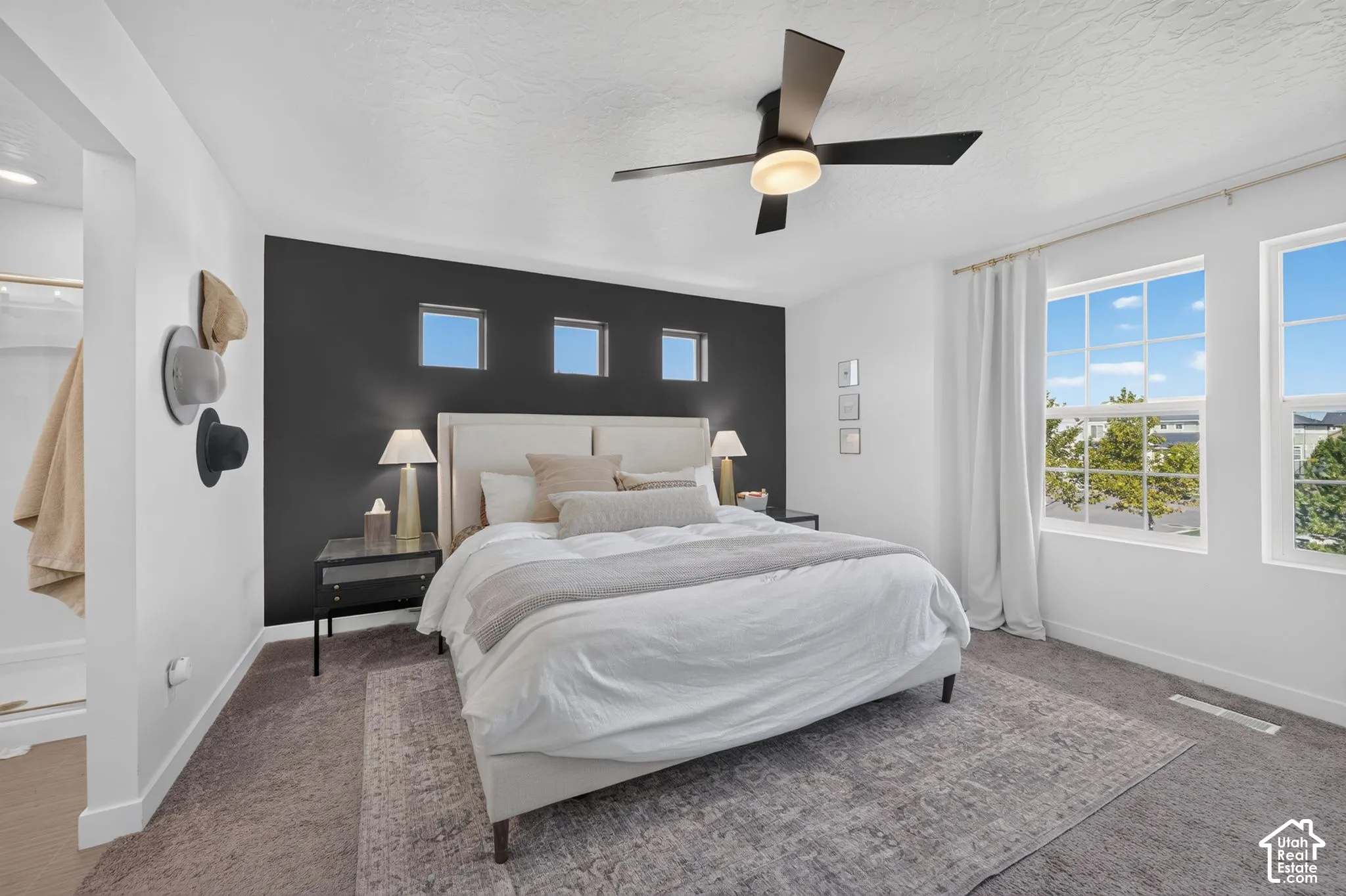 Accent wall, transom windows, ceiling fan with integrated lighting, two large windows, and wall-to-wall carpeting