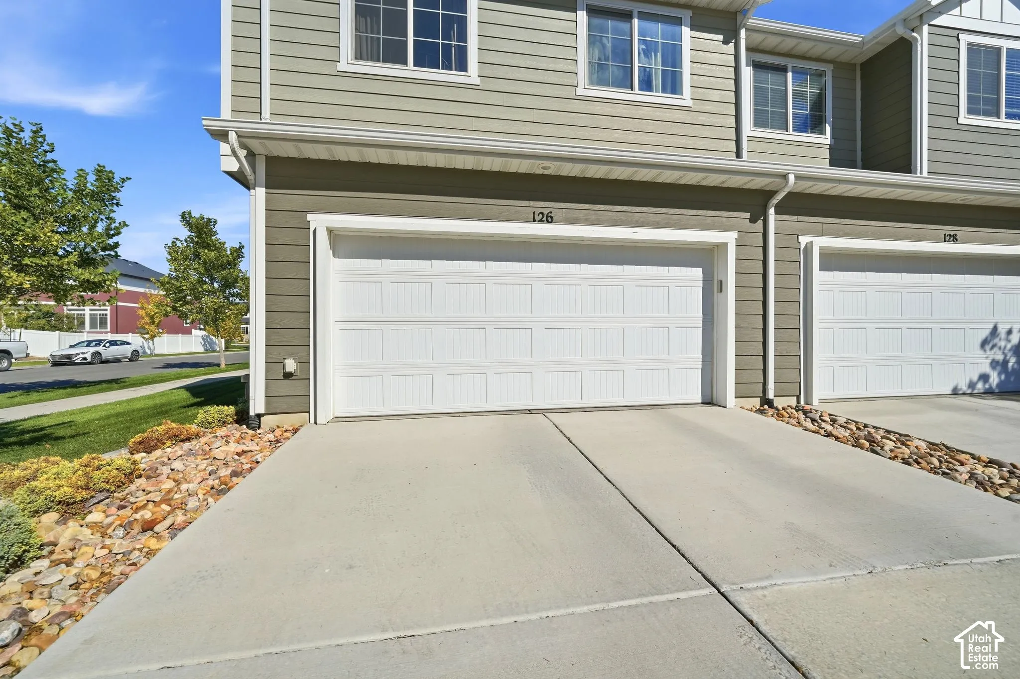 Attached garage with a panel door, concrete driveway, and light gray siding
