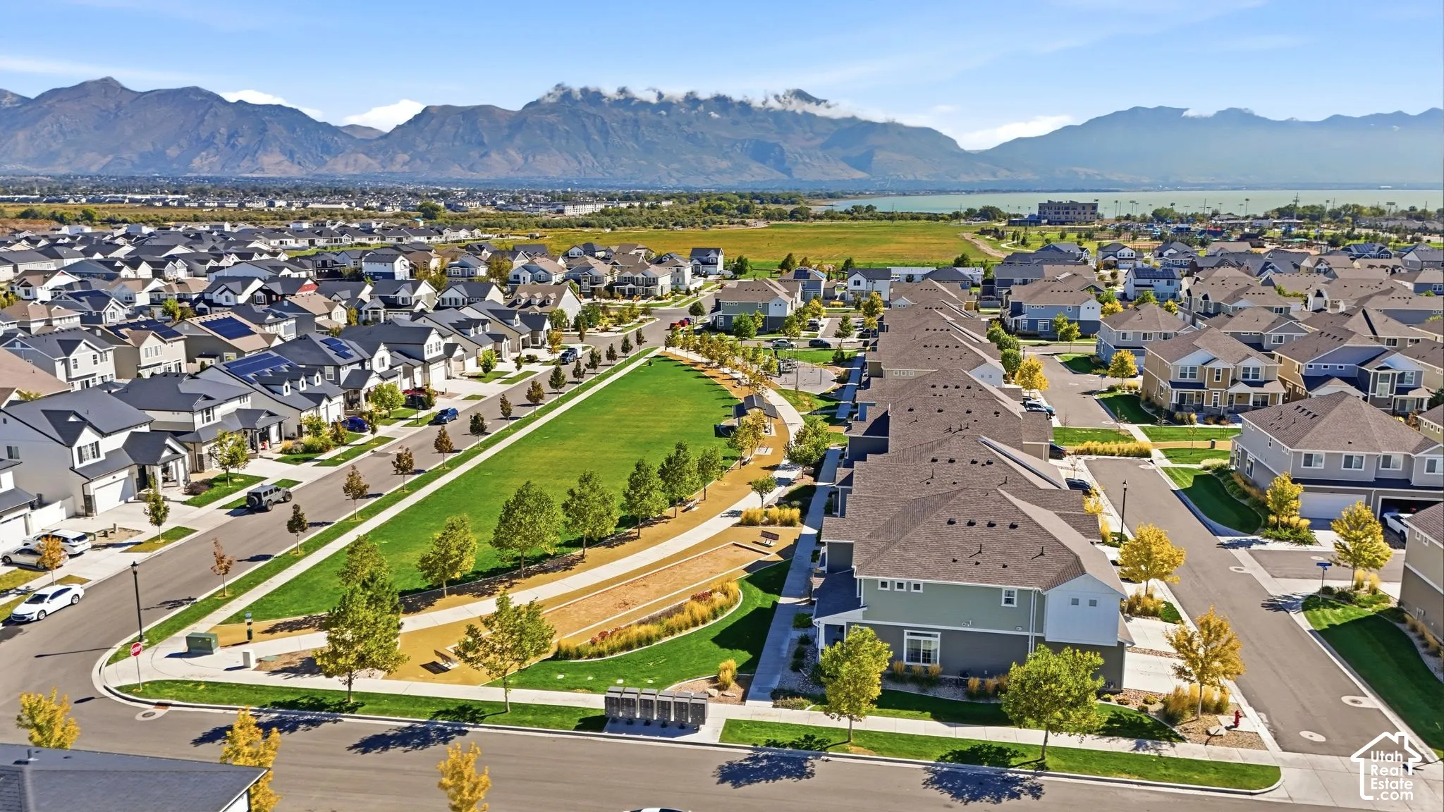Residential neighborhood featuring a central green space, paved streets, and mountain backdrop