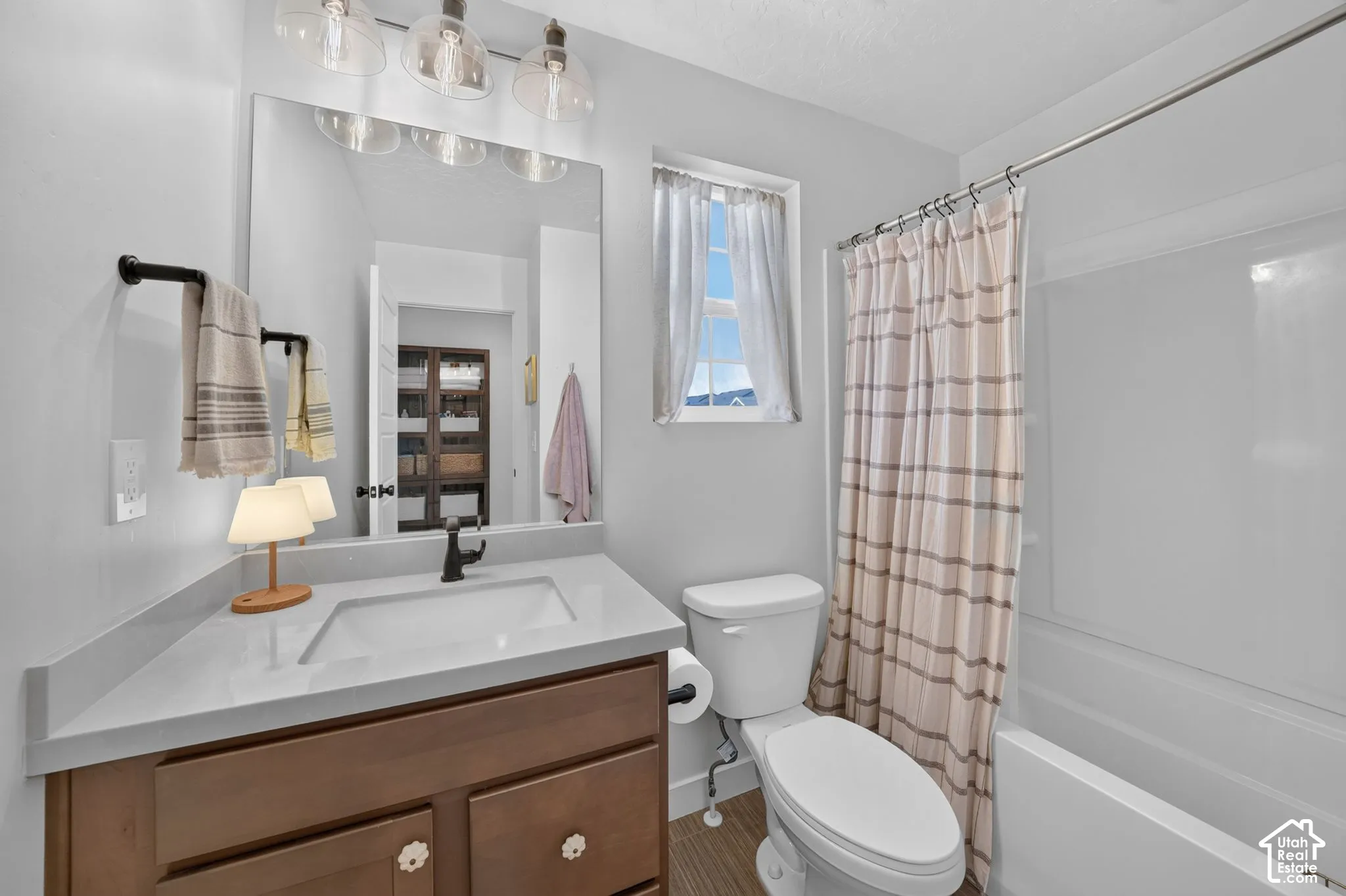 Wood-finish flooring, light grey walls, and a white vanity with a white countertop