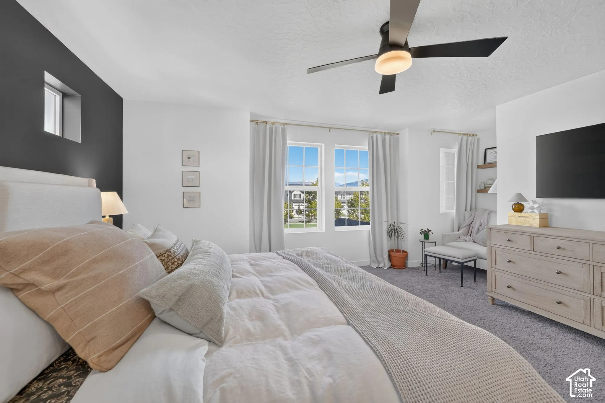 Carpeted flooring, contemporary ceiling fan, dual windows with curtains, recessed window, and accent wall