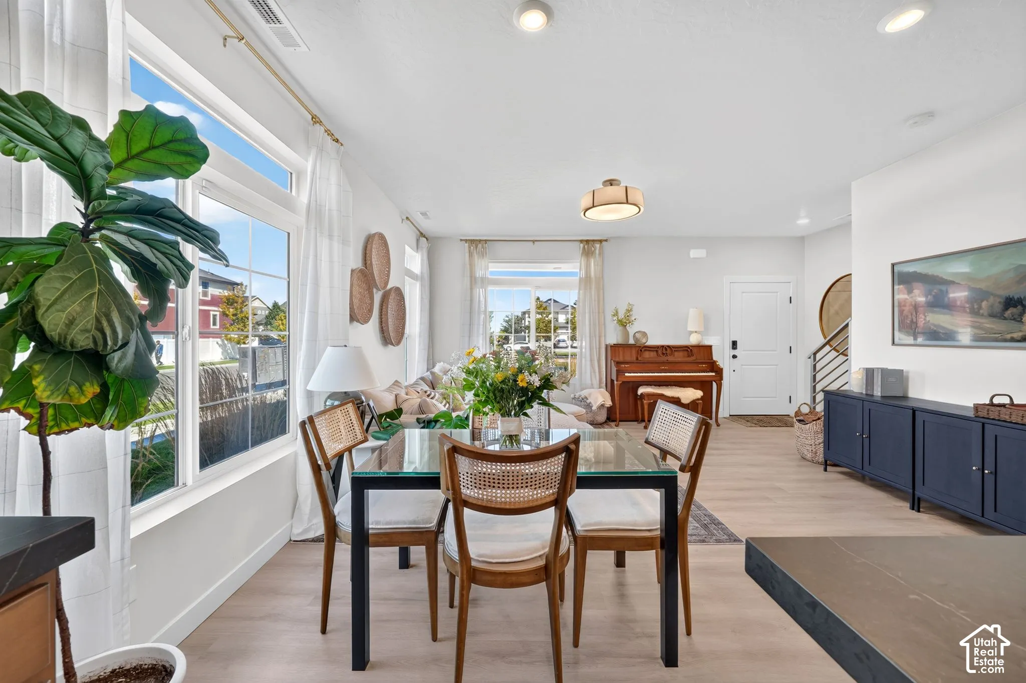 Recessed lighting, wood-finish flooring, large windows, white interior walls, and a modern staircase with metal railings