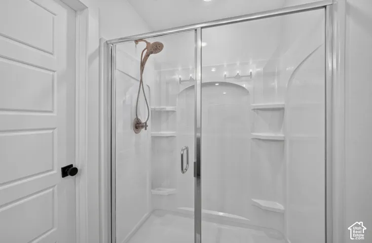 Shower enclosure with glass sliding doors, integrated shelving, and a bronze-finish showerhead