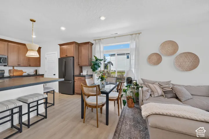 Open-concept living area featuring wood-finish flooring, a kitchen island with seating, recessed lighting, and a modern pendant light fixture