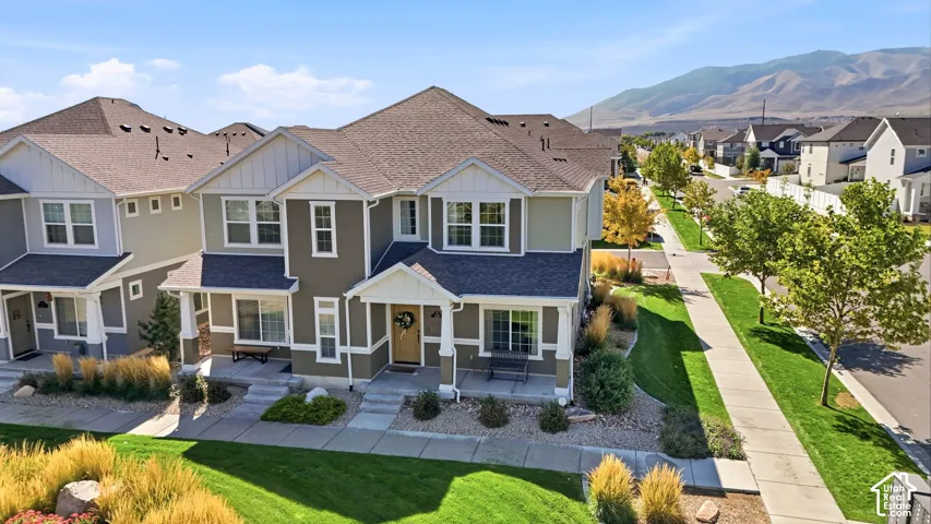 Two-story residence featuring a covered front porch, gabled roofline, and established landscaping