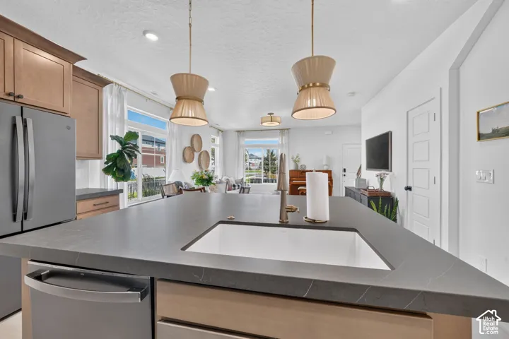 Kitchen island with an undermount sink, stainless steel faucet, and pendant lighting