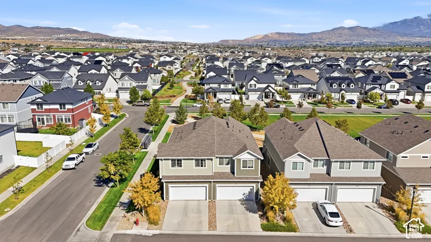 Residential community featuring multiple-story homes with attached garages, paved streets, and green spaces