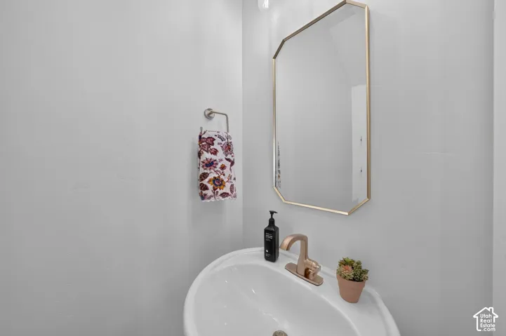 Pedestal sink with a rose gold-finish faucet and an octagonal mirror with a gold-finish frame