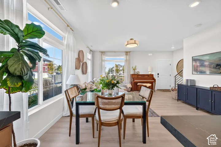 Recessed lighting, wood-finish flooring, large windows, white interior walls, and a modern staircase with metal railings