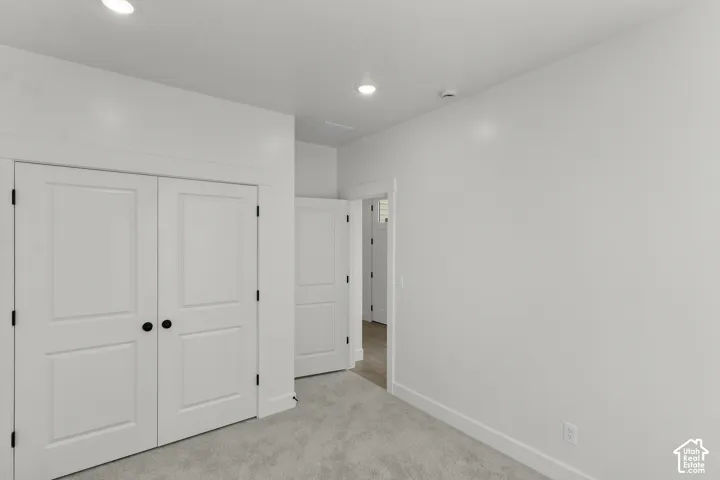 Recessed ceiling lighting, white painted interior doors, black door hardware, plush gray carpeting, and white trim