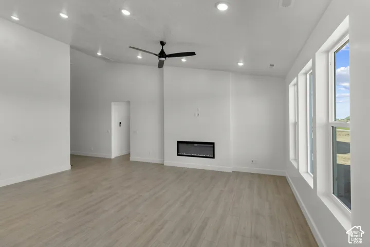 Recessed lighting, a ceiling fan, light wood-finish flooring, a built-in electric fireplace, and multiple windows