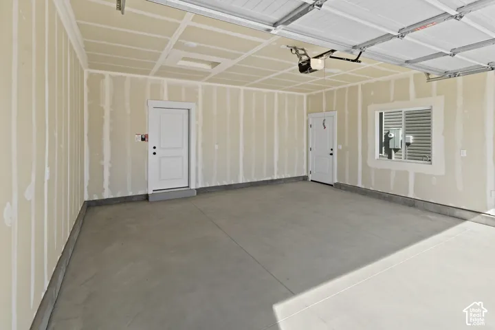 Spacious garage with an overhead door, smooth concrete flooring, and two interior access doors